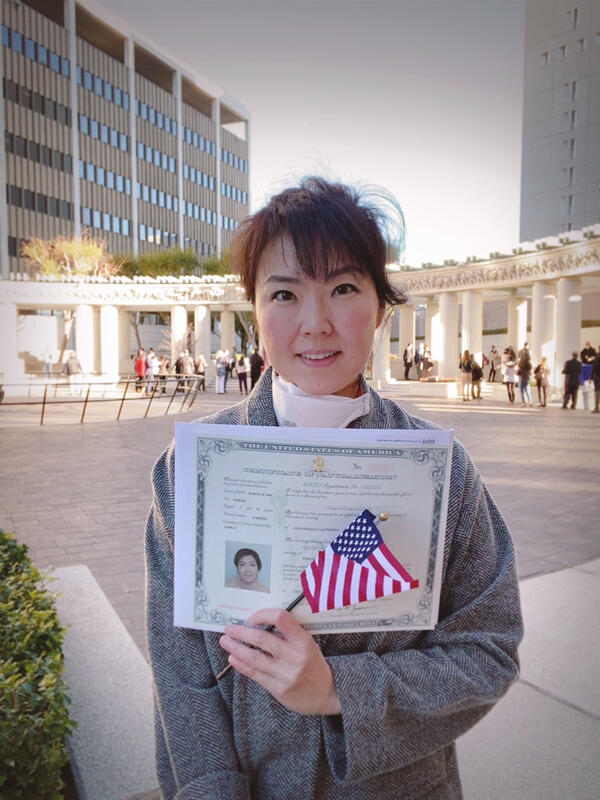 female student holding citizenship certificate and flag